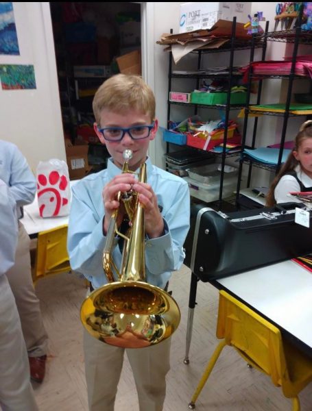 Student horn player in the band practice room